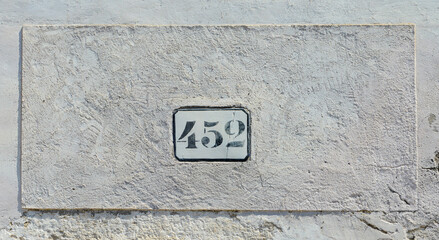 House number 452 sign to old white wall