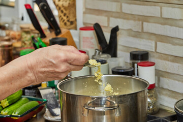 Fototapeta na wymiar Chef tosses the chicken broth powder into pot on gas stove