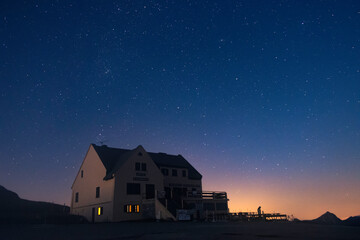 A house just after sunset with bright stars above and orange glow