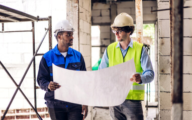 Professional of team architect industrial engineer cargo foreman in helmet working new construction project architectural plan with blueprint and construction tool at the building construction site