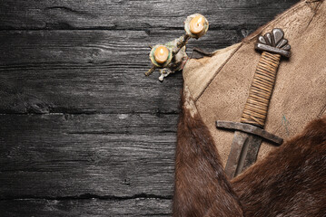 Ancient sword wrapped in the beast skin on the flat lay table background with copy space.
