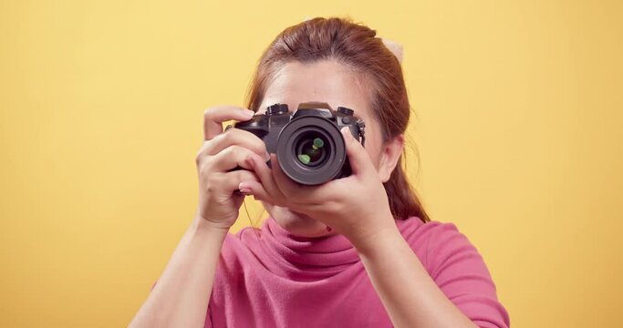 Asian gorgeous young woman in a studio shot over an isolated yellow background using a digital camera with copy space for advertising.