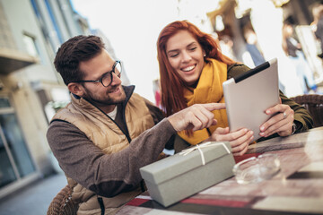 Happy young couple using a digital tablet together at a coffee shop.