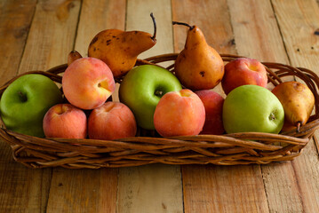 Fruits in wicker basket on wooden table.