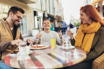 Portrait of happy family spending time in pizzeria outdoors