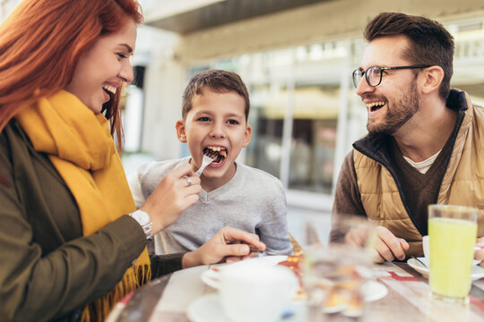 Portrait of happy family spending time in pizzeria outdoors