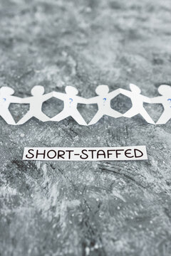 staff shortages and business struggling after the pandemic, paper people chain with question marks on some workers and Short-staffed text on black background