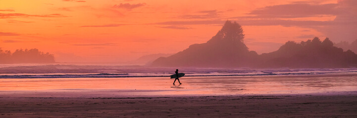 Tofino Vancouver Island Pacific rim coast, surfers with surfboard during sunset at the beach,...