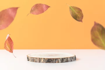 Tuinposter Wood podium on orange background with colorful falling leaves.  Concept scene stage showcase, product, promotion sale, presentation, beauty cosmetic. Wooden stand studio empty © Anna Puzatykh