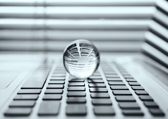 Close up of crystal ball on laptop. Glass sphere on the laptop keyboard with computer background. ...