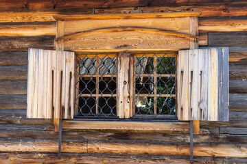 a window in an old wooden house on a clear sunny summer day.  a window in a rustic wooden house. The old window of old wooden house. Background of wooden walls. old wooden window on a cabin