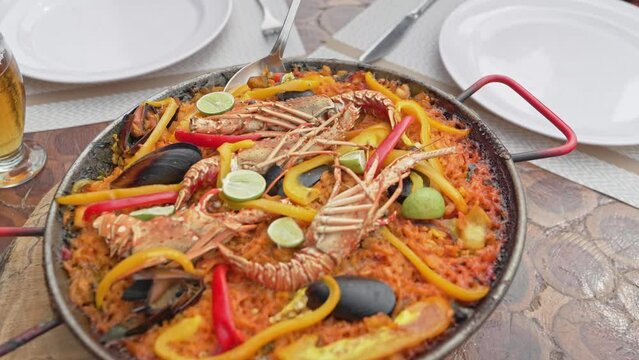 Eating Mouthwatering Paella Royale With Lobsters And Mussels Served On Dining Table. dolly-in shot