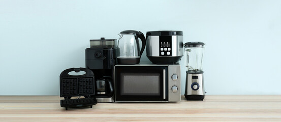 Different household appliances on table against light background