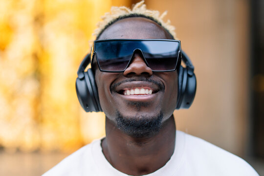 Happy black man listening to music on street