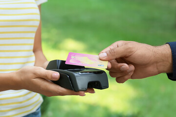Man paying with credit card via payment terminal outdoors, closeup