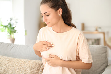 Young woman suffering from breast pain at home