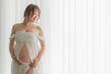 マタニティフォトの撮影をするアジア人妊婦の女性（横顔）
