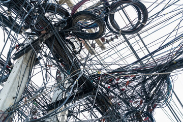 Tangled electrical wires on urban electric pole. Disorganized and messy to organization management...
