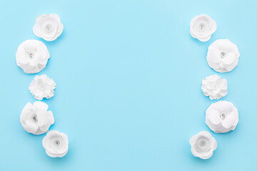 Fototapeta na wymiar Frame made of paper flowers on blue background