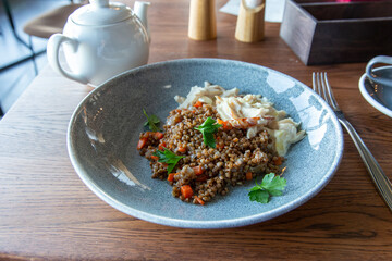 Delicious buckwheat porridge with sauce and parsley in a blue plate