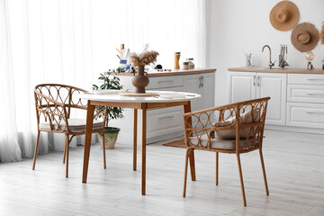 Interior of cozy kitchen with dining table and rattan armchairs