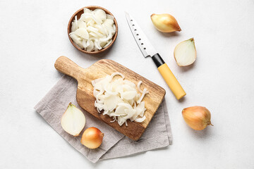 Composition with wooden board of cut onion on light background