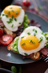 Tasty breakfast - fried egg toasts, bacon, tomatoes on wooden kitchen table