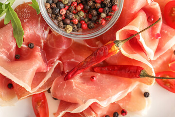Slices of delicious jamon and bowl of peppercorns, closeup