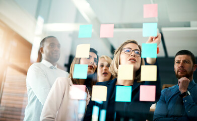 Creative group or business team planning for innovation with sticky notes on glass wall. Coach or...