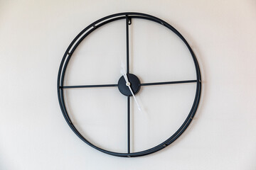 Metal wall clock on a white wall.