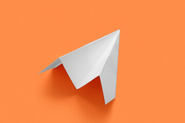 White paper plane on orange background