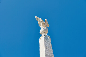 Stone eagle statue on a pole. Eagle on pole sunny blue sky background. Stone-made monument with...