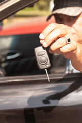Car key in a man's hand with car.