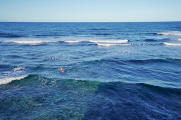 It's time for surfing! Young man swimming on a surf board.