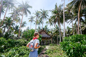 Naklejka na ściany i meble Tropical vacation. Young woman enjoying the view of beautiful coconut palms plantation.