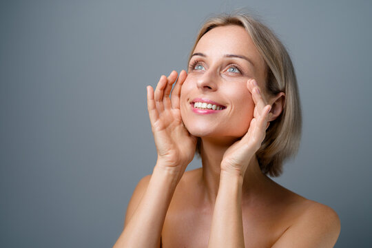 Skin Care. Blonde Woman With Beauty Face Touching Healthy Facial Skin. No Makeup. Grey Background.