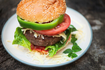 appetizing burger close-up on a plate on an old wooden background