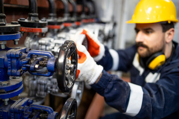 Professional worker tightening industrial valve in factory.