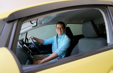 Asian man smiling to the camera from inside his car
