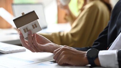 Close up view businessman or investor with small house model in his hand. Real estate, mortgage loan and home insurance concept