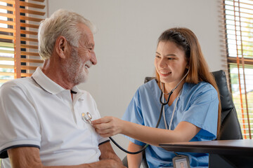Assistance doctor uses stethoscope to senior old elderly man after treatment and checkup. Caregivers smile to encourage and care for patient. Health insurance, nursing homes