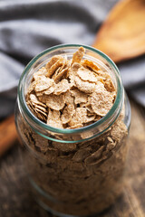Whole grain cereal flakes. Wholegrain breakfast cereals in jar on kitchen table.