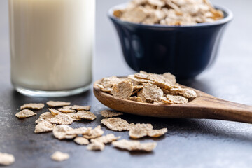 Whole grain cereal flakes. Wholegrain breakfast cereals in wooden spoon on kitchen table.