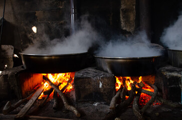 big cauldrons over fire, cooking. Wood fire.
