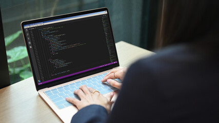 Over shoulder view of female software developer working on web site project, programming on desktop computer in startup company