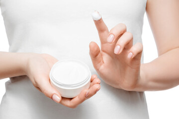 Close up shot of a woman in white t-shirt holding a jar of hand cream, isolated on white. Short natural nails.