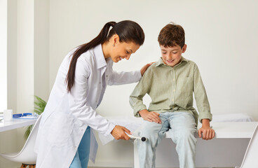 Happy, friendly doctor examining a child. Professional neurologist uses a hammer to test the knee...
