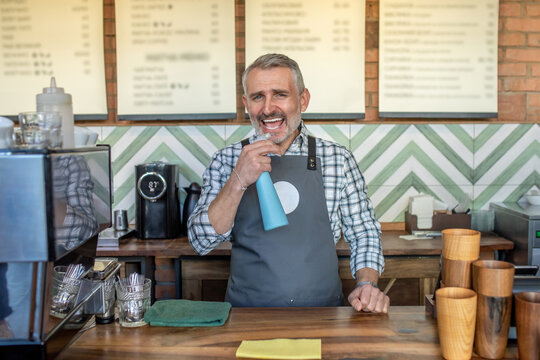 Man in plaid shirt and apron hoding a spray