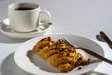 Maple and pecan plait served on a plate with a cup of coffee