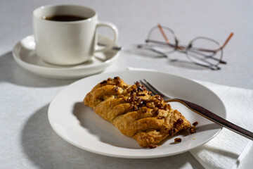 Maple and pecan plait served on a plate with a cup of coffee
